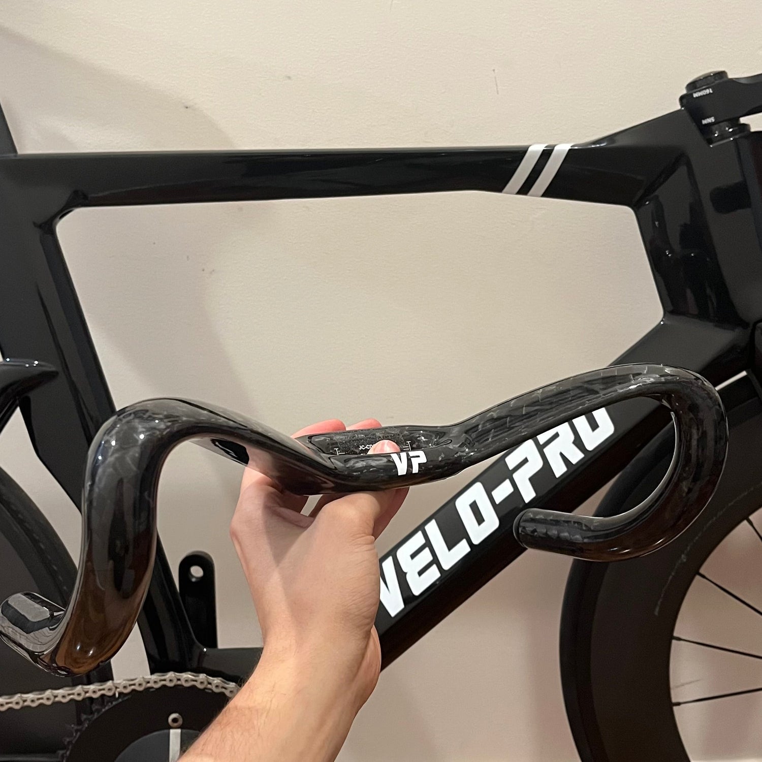 Person adjusting a bicycle handlebar with 'VELO-PRO' branding on a black bike.
