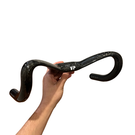 Hand holding a black bicycle handlebar with 'VP' branding on a white background